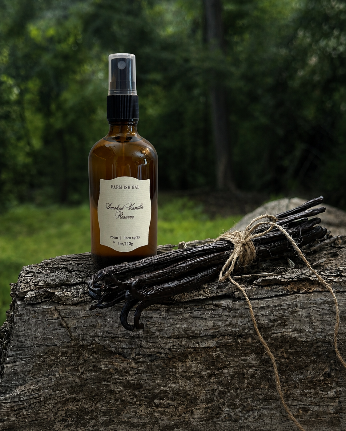 Fine mist spray bottle with a label that says Smoked Vanilla Reserve with vanilla beans on a wooden log outdoors